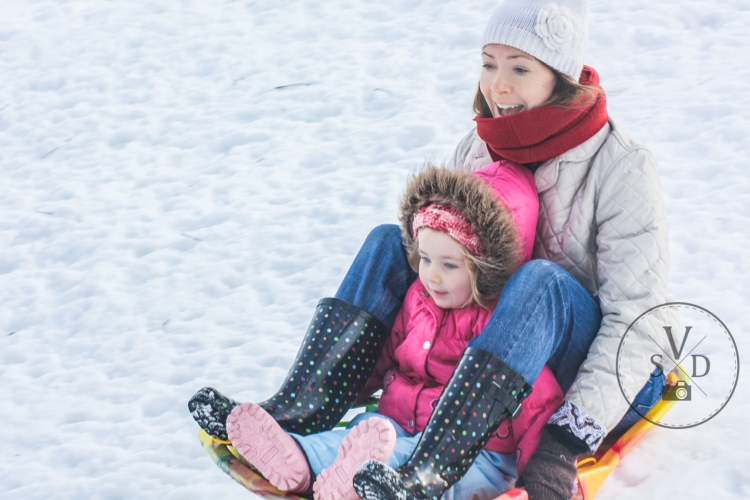 Mom and daughter sled down a snowy hill. Not So SAHM