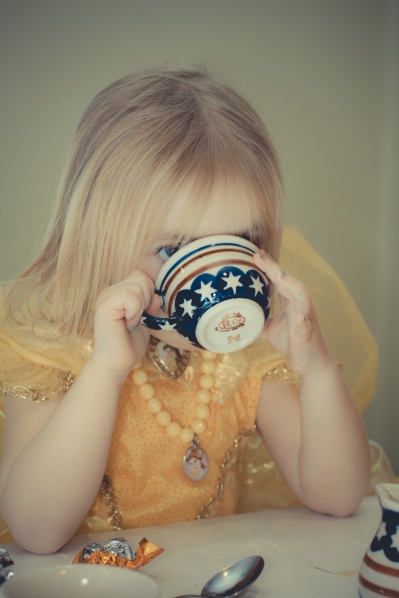 A young girl sips tea during a tea time play date. Not So SAHM